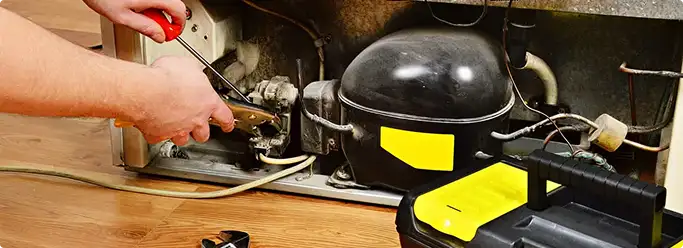 Refrigerator repair technician fixing the compressor and wiring in Valhermoso Springs, AL