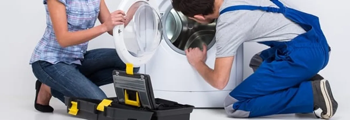 Washer repair technician inspecting a front-load washing machine with tools in Huntsville, AL