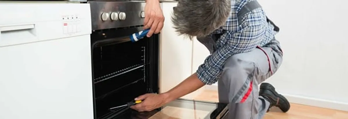Oven repair technician inspecting and servicing an electric oven in Huntsville, AL