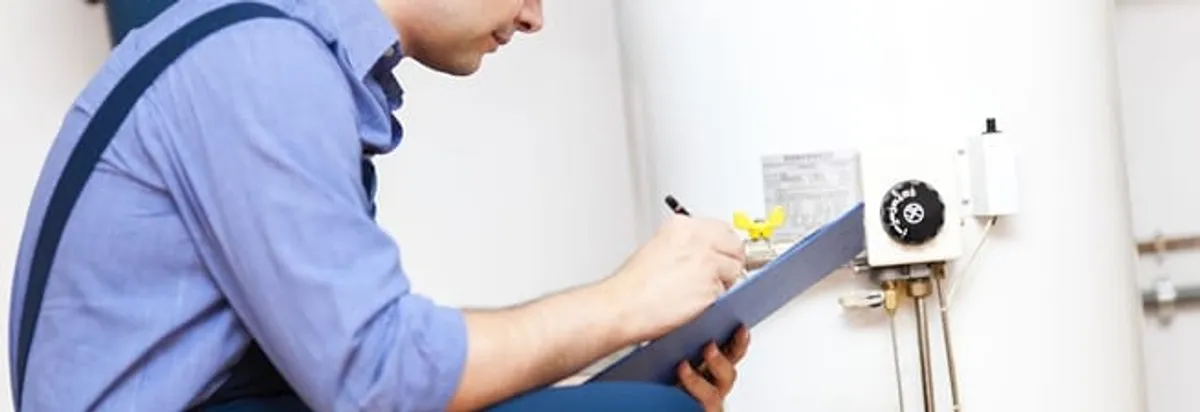 Water heater repair technician inspecting the unit and recording service notes in Huntsville, AL
