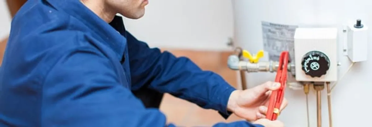 Water heater repair technician adjusting the temperature control and gas valve in Huntsville, AL